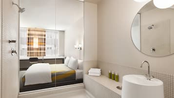 A modern bathroom with a large bathtub, a round mirror, and a window with a view of the city.
