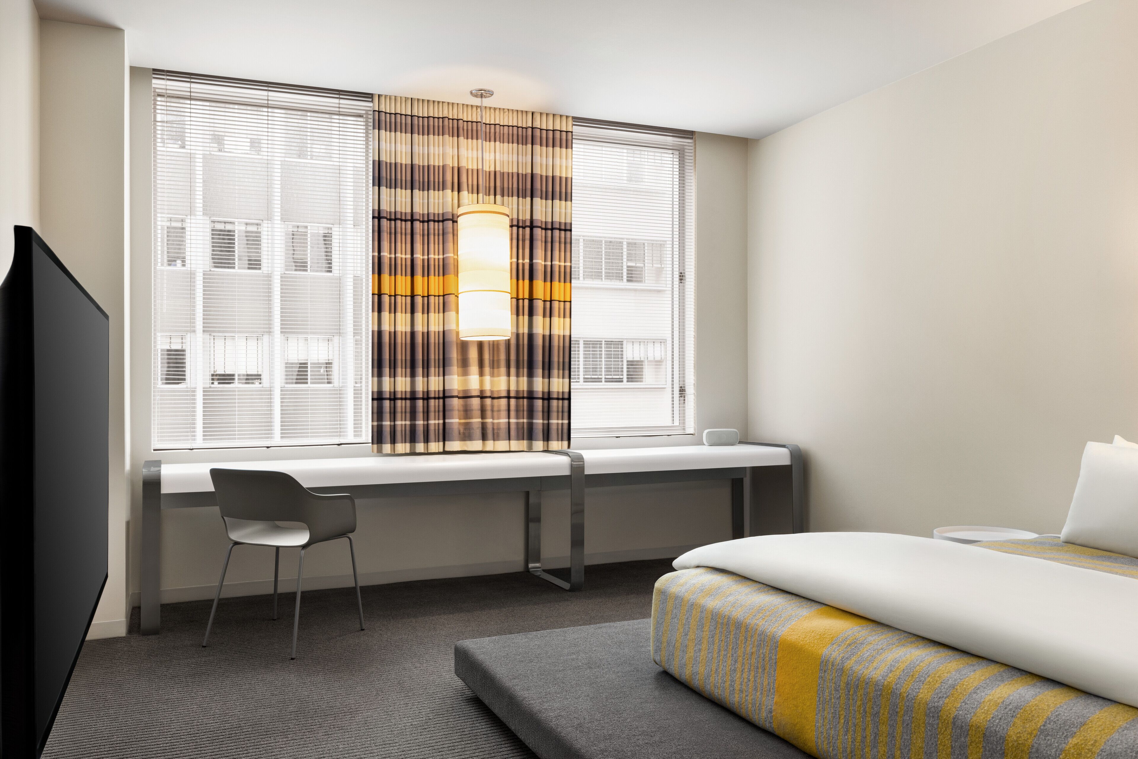 Una habitación de hotel con una cama, un escritorio y una silla.