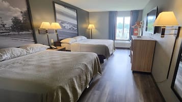 Una camera d'albergo con due letti, una scrivania, un comò e un'ampia finestra con tende.