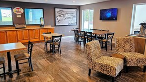 A restaurant with wooden tables and chairs, a counter with a menu, and a TV on the wall.