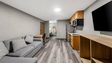 Un espace de vie compact avec un canapé gris, des meubles en bois et un téléviseur à écran plat.