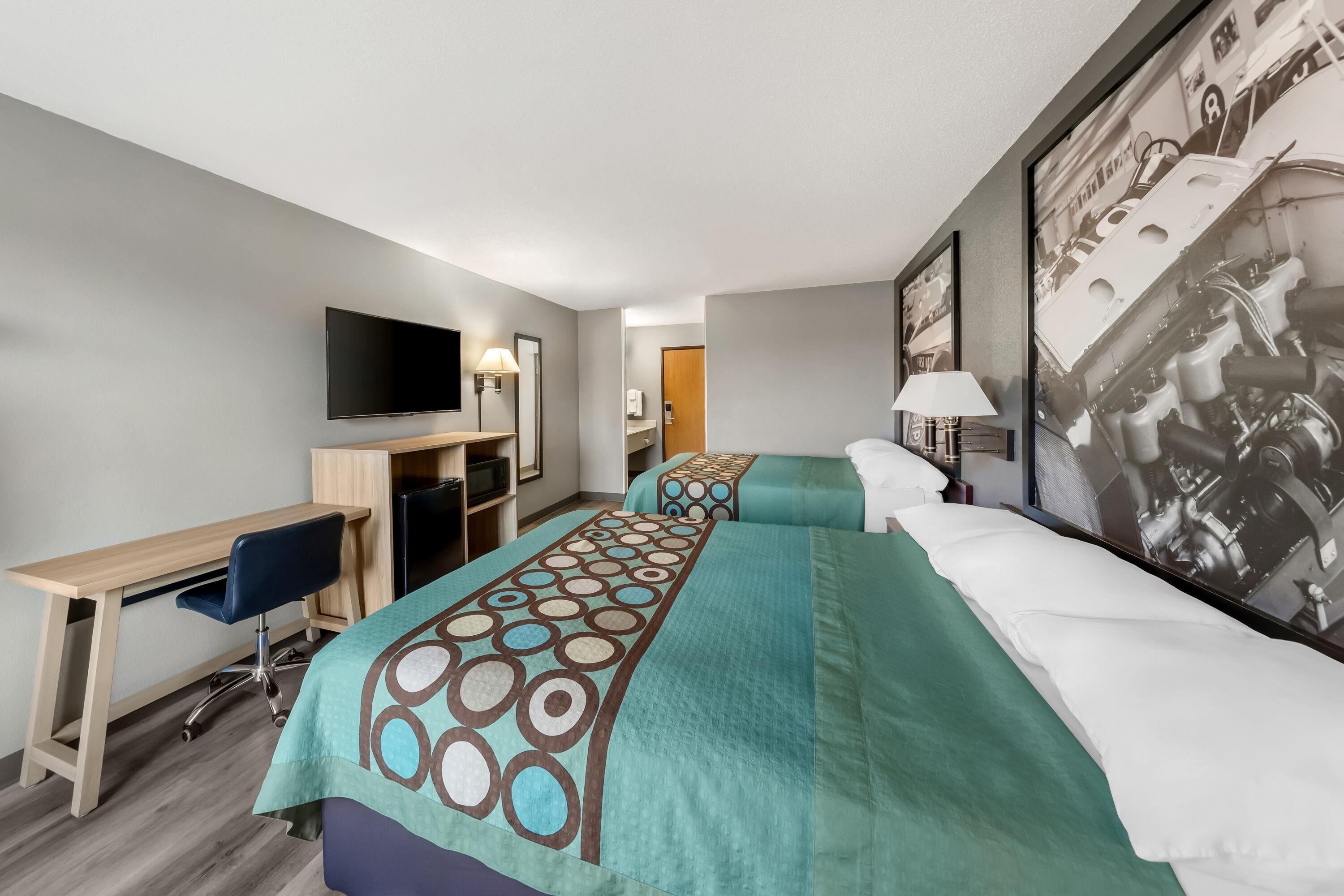 A hotel room with a bed, a desk, a chair, a television, and a bathroom.