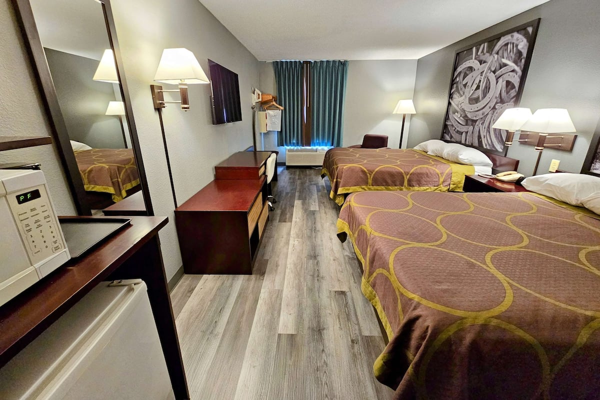 A hotel room with a bed, desk, chair, and a microwave.