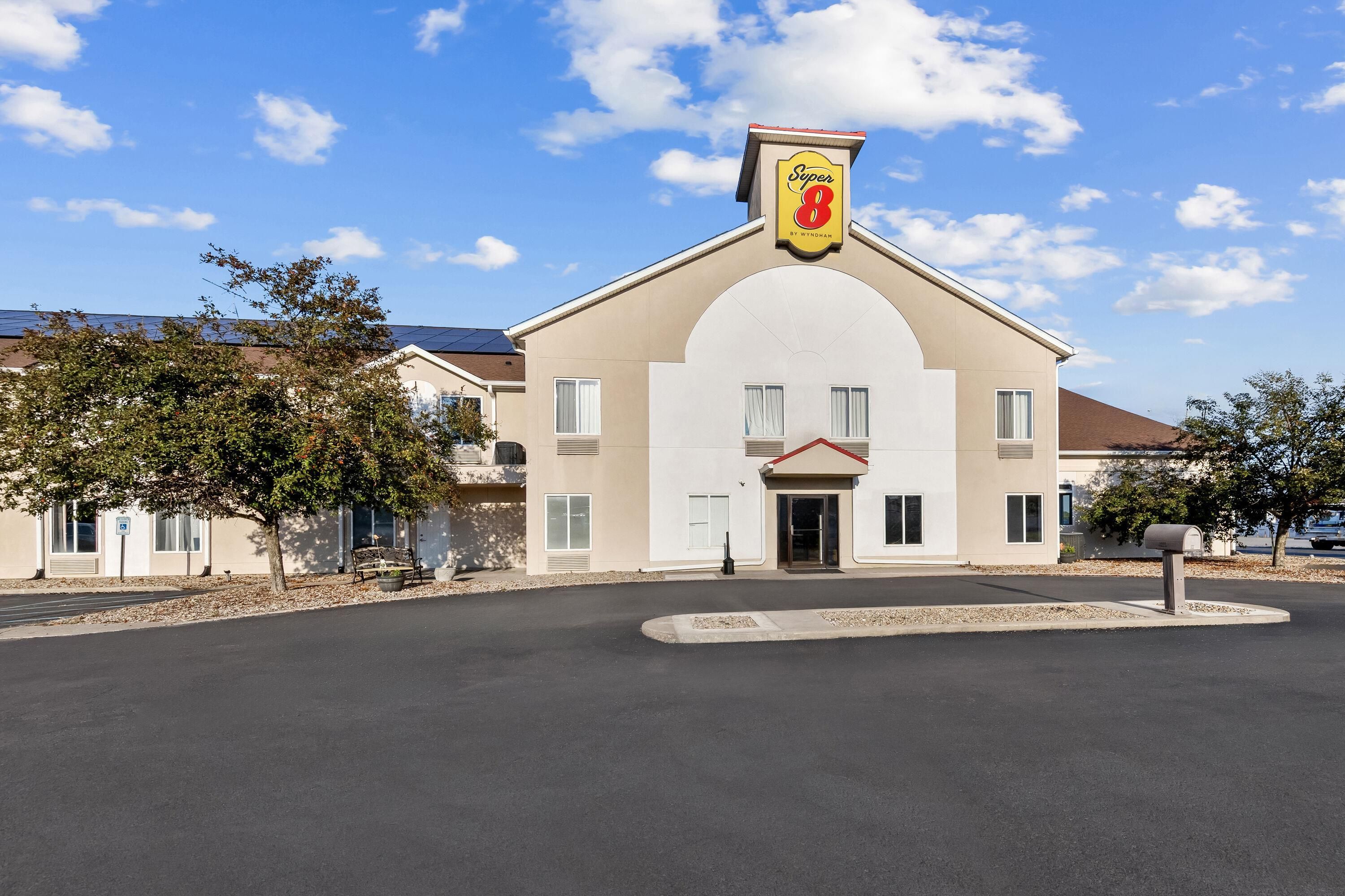 Un hotel con un llamativo letrero de 'Super 8', una entrada principal y un área de estacionamiento.