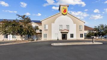 Un hotel con un llamativo letrero de 'Super 8', una entrada principal y un área de estacionamiento.