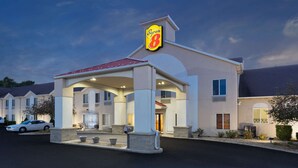 A Super 8 hotel with a covered entrance, multiple windows, and a parking lot with cars.