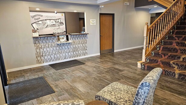 A reception area with a reception desk, a wooden door, a staircase, and patterned seating.