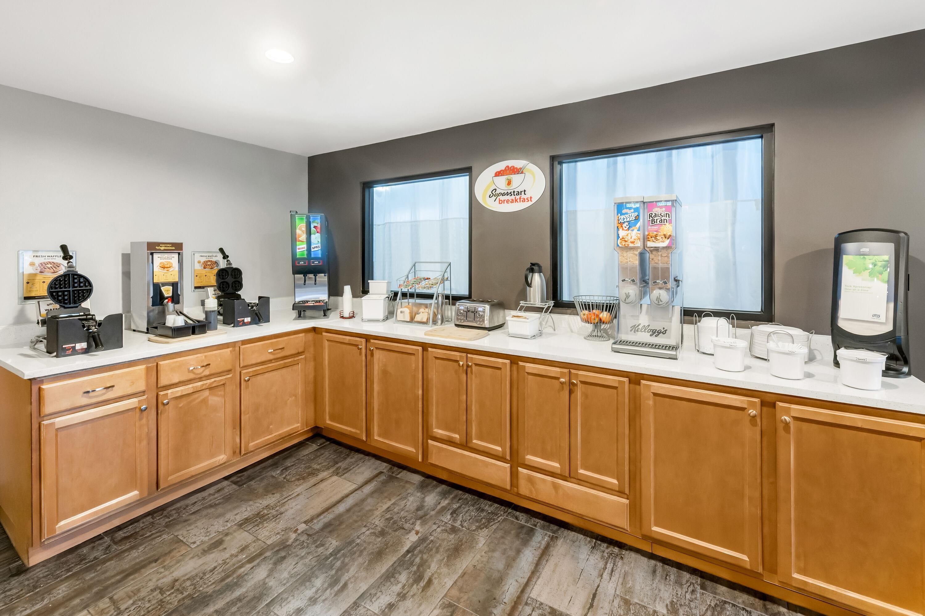 A breakfast bar with waffle makers, coffee machines, and cereal dispensers.