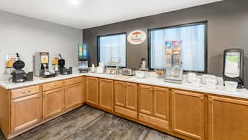 A breakfast bar with waffle makers, coffee machines, and cereal dispensers.
