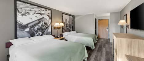 A hotel room with two beds, a desk, a TV, and a large wall art piece.