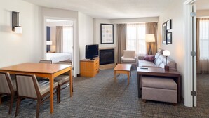 Une chambre d’hôtel équipée d’une table à manger, de chaises, d’un canapé, d’une télévision, d’une cheminée et d’une porte.