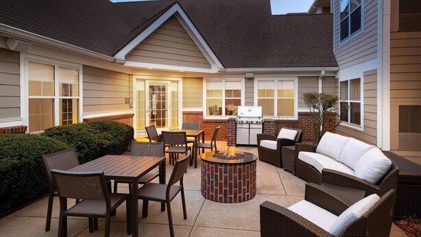 Un espace extérieur aménagé avec une terrasse, un foyer, des sièges et un barbecue.