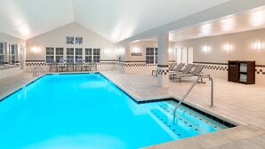 Une piscine intérieure à l’eau claire, avec des murs carrelés et un panneau indiquant qu’il est interdit de plonger.