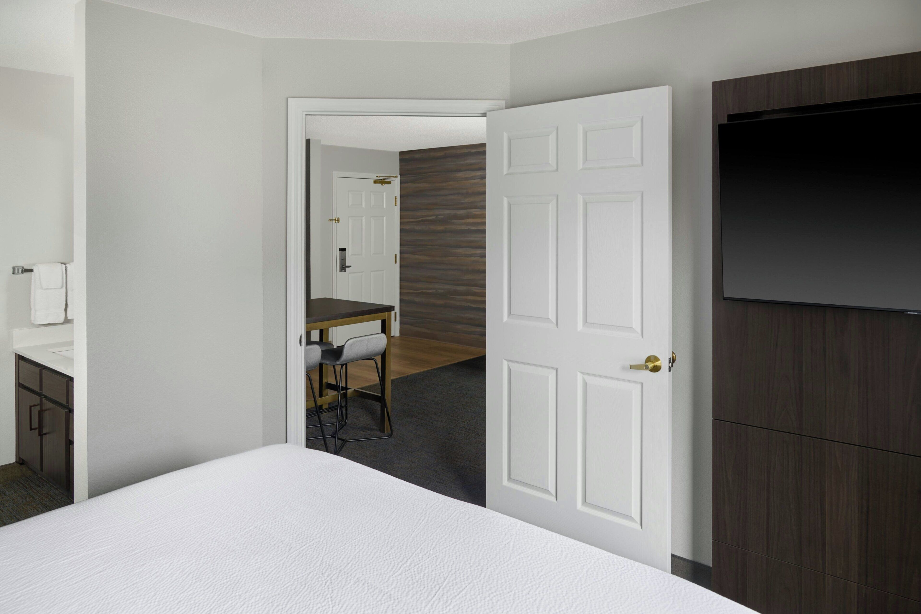A hotel room with a bed, a desk with chairs, a television, and a wardrobe.