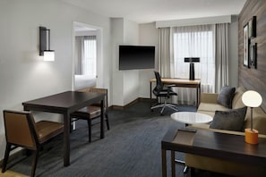 A hotel room with a flat-screen TV, a desk, a sofa, a coffee table, and a lamp. - Residence Inn by Marriott Huntsville (Huntsville)