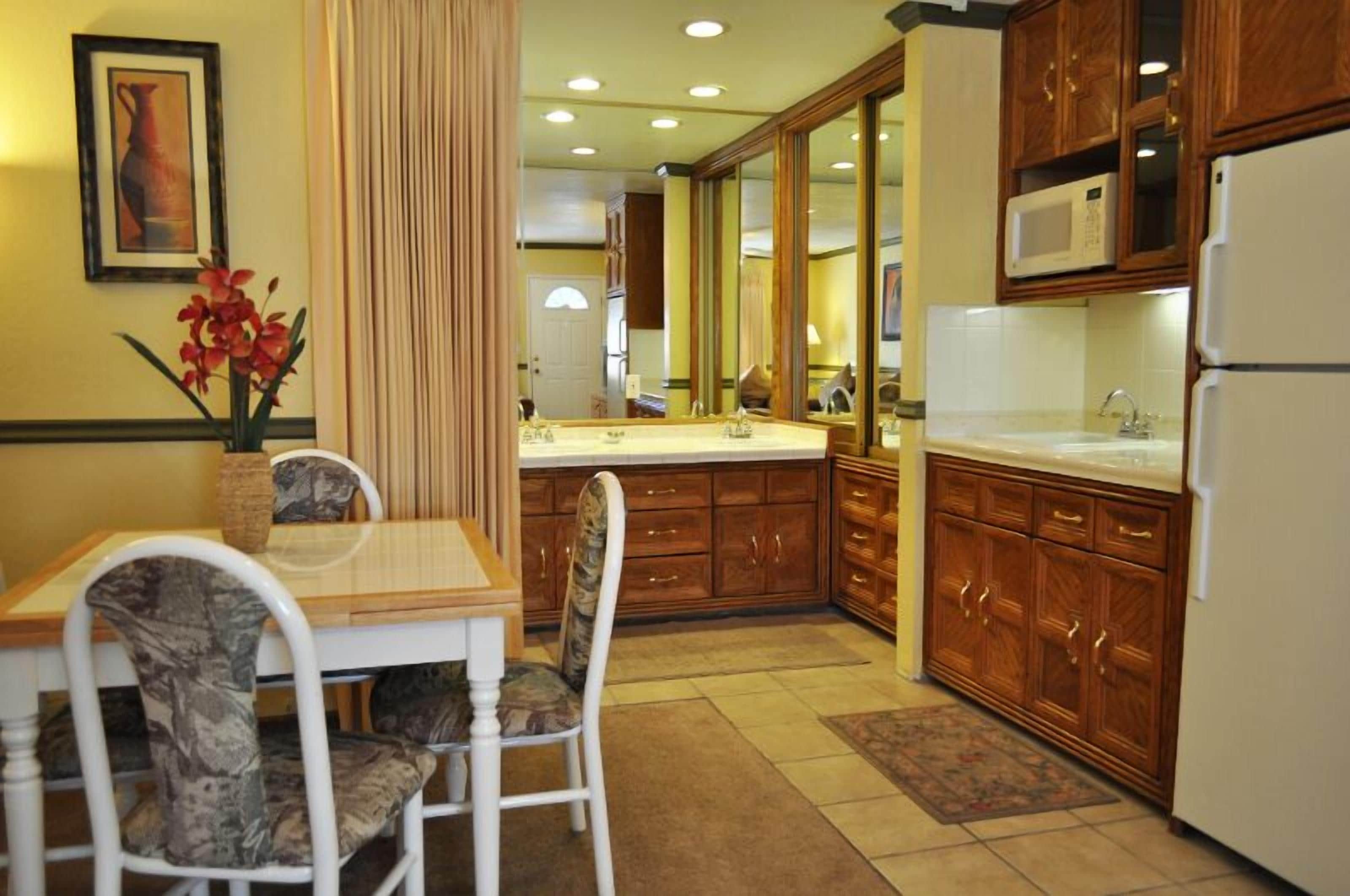 Una cucina con mobili in legno, un frigorifero bianco e un'area pranzo con tavolo e sedie.