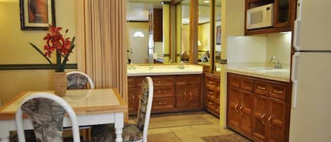 Una cocina con armarios de madera, un refrigerador blanco y un comedor con mesa y sillas.