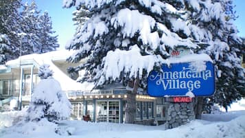 Placa coberta de neve para Americana Village, com base de pedra e a inscrição vermelha 'VACANCY'.