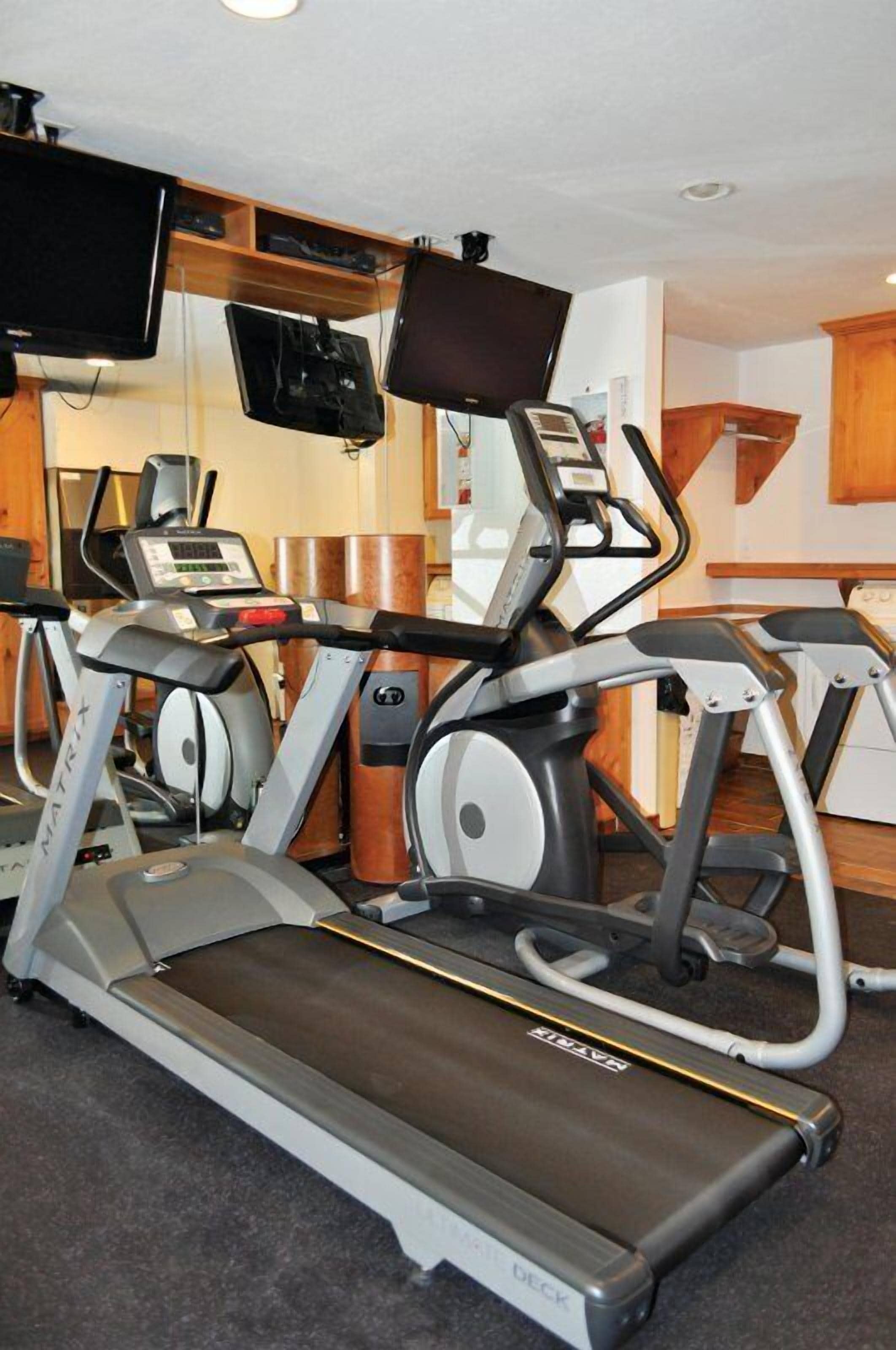 A home gym with a treadmill, stationary bikes, and a weight bench.
