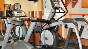 A home gym with a treadmill, stationary bikes, and a weight bench.