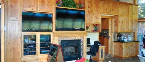 A wooden interior with a fireplace, television, and kitchen area.
