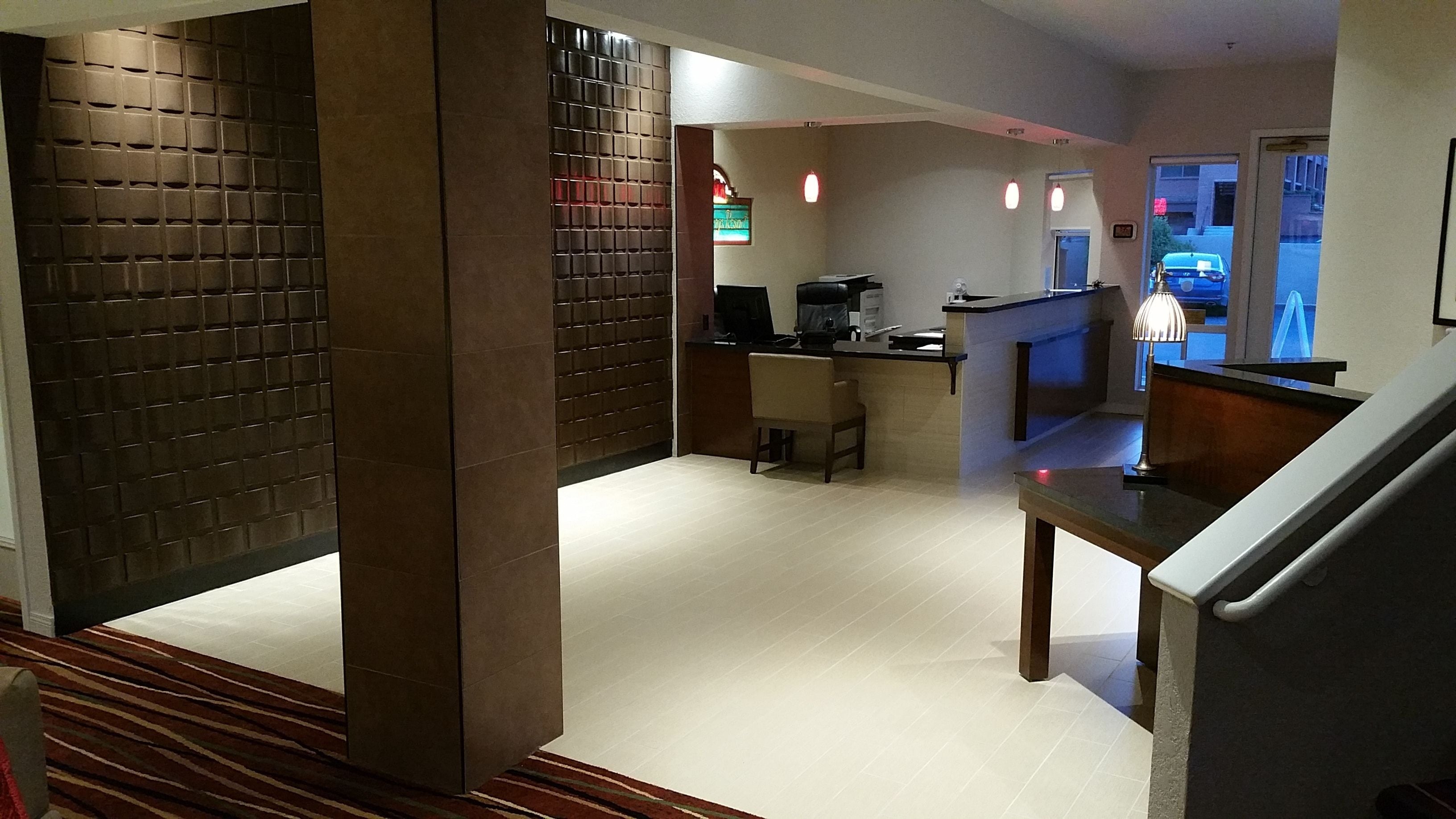 Un moderno vestíbulo de hotel con una recepción, un área de descanso y una escalera.