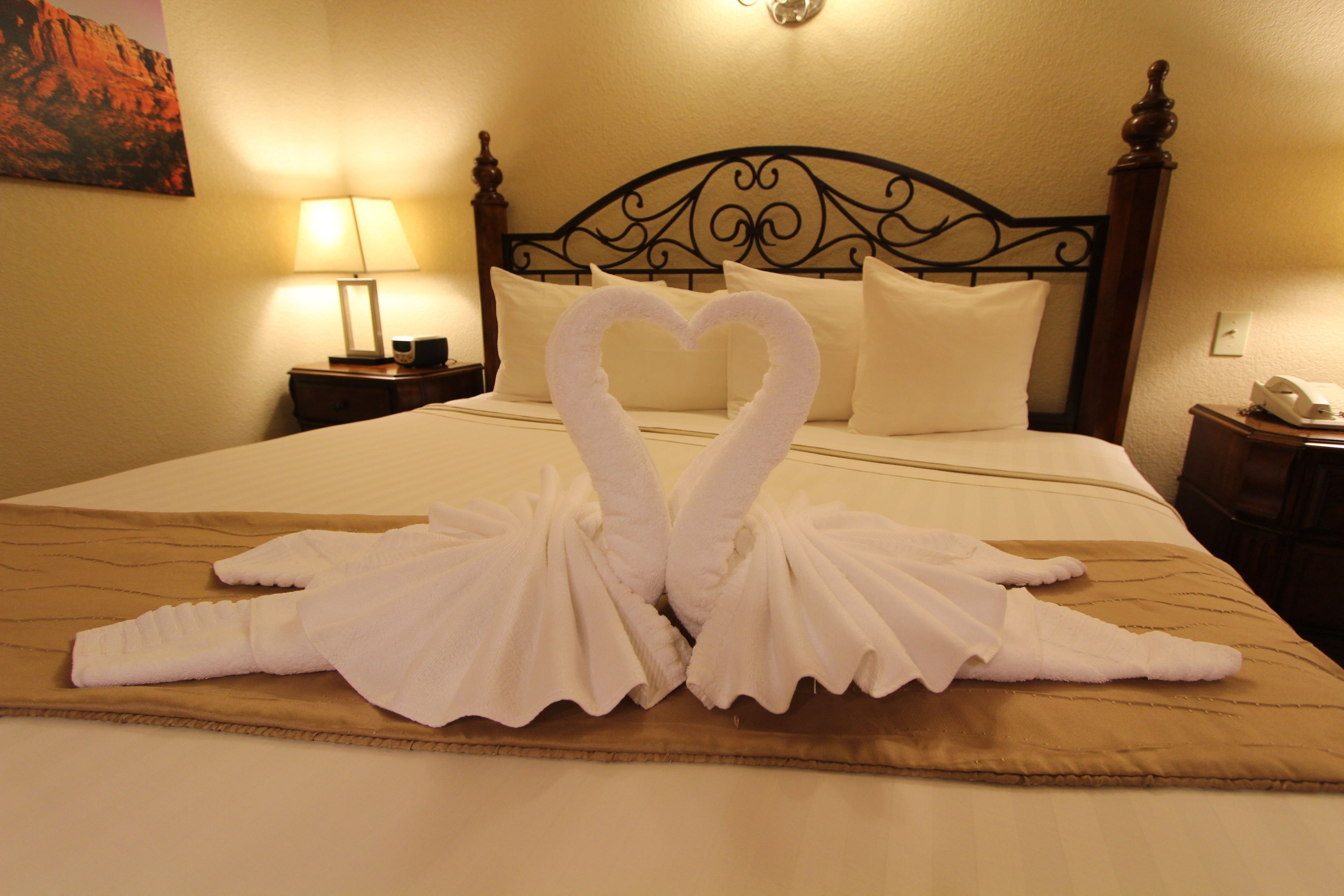 A hotel room with a bed, a nightstand, and a wall-mounted lamp.