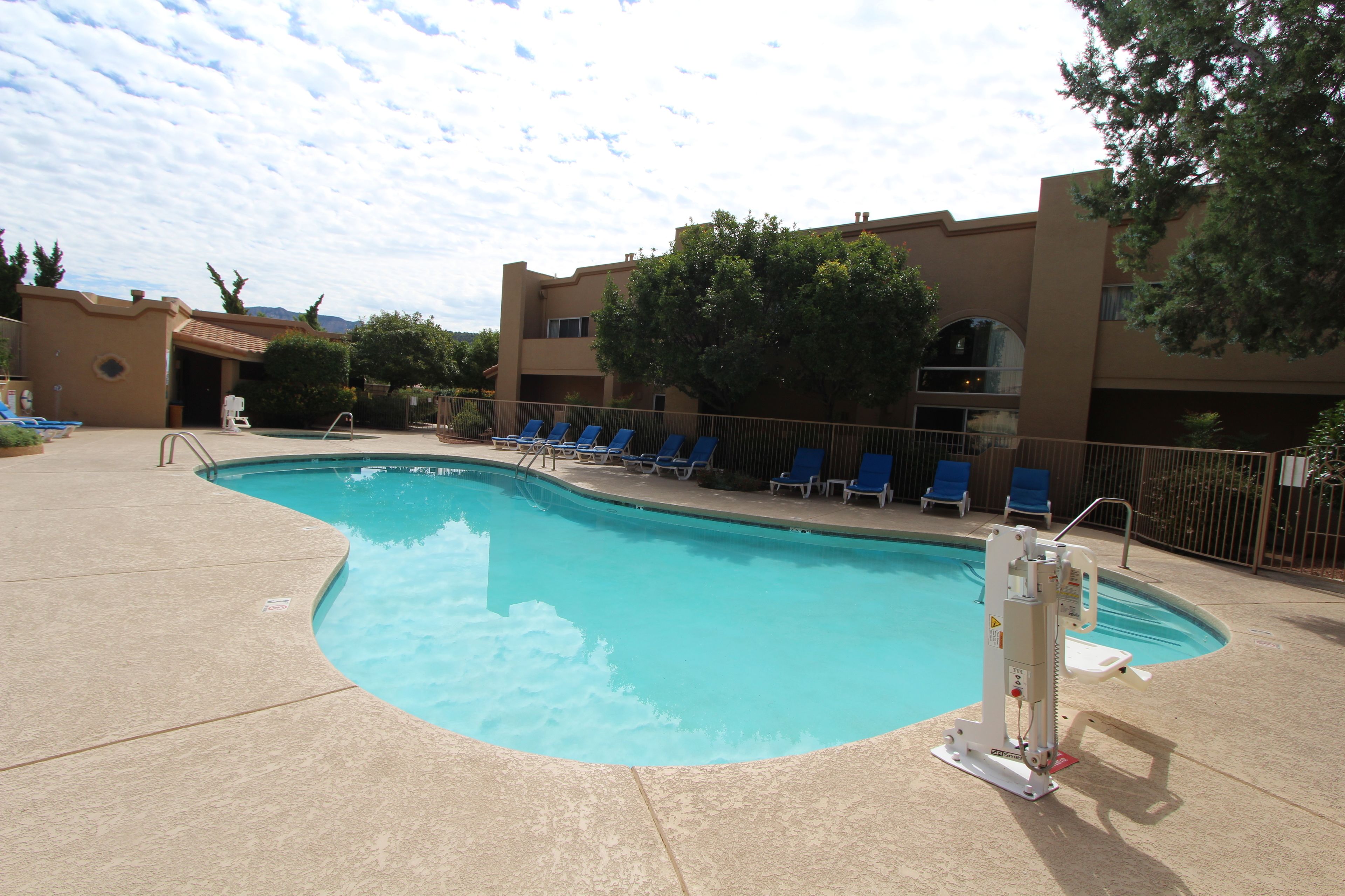 A swimming pool with blue chairs and a lifeguard stand.