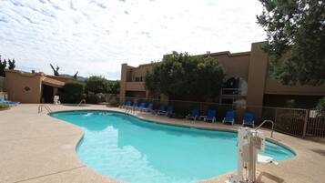 A swimming pool with blue chairs and a lifeguard stand.