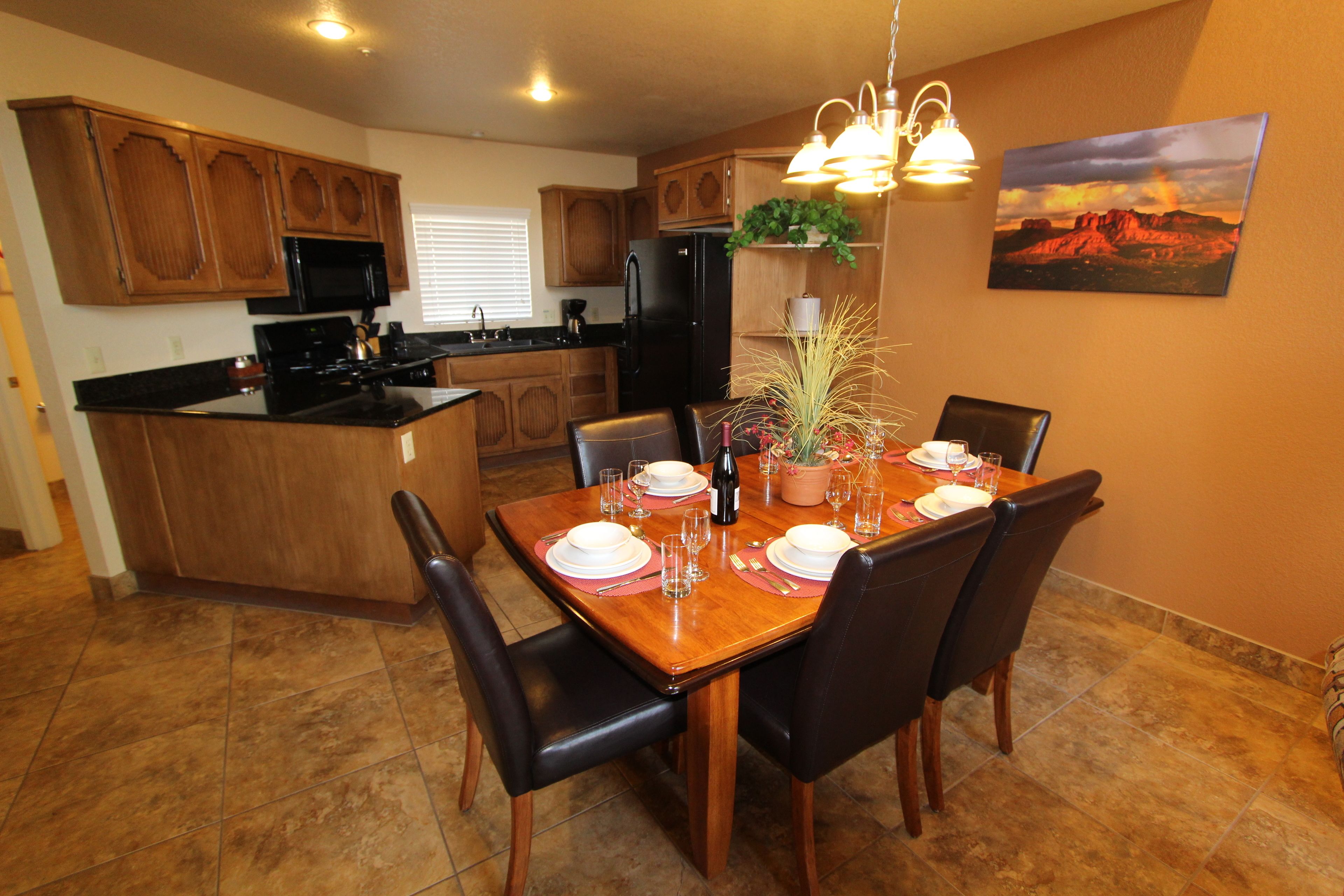 A modern kitchen with wooden cabinets, a central island, and a dining area with a wooden table set for four.