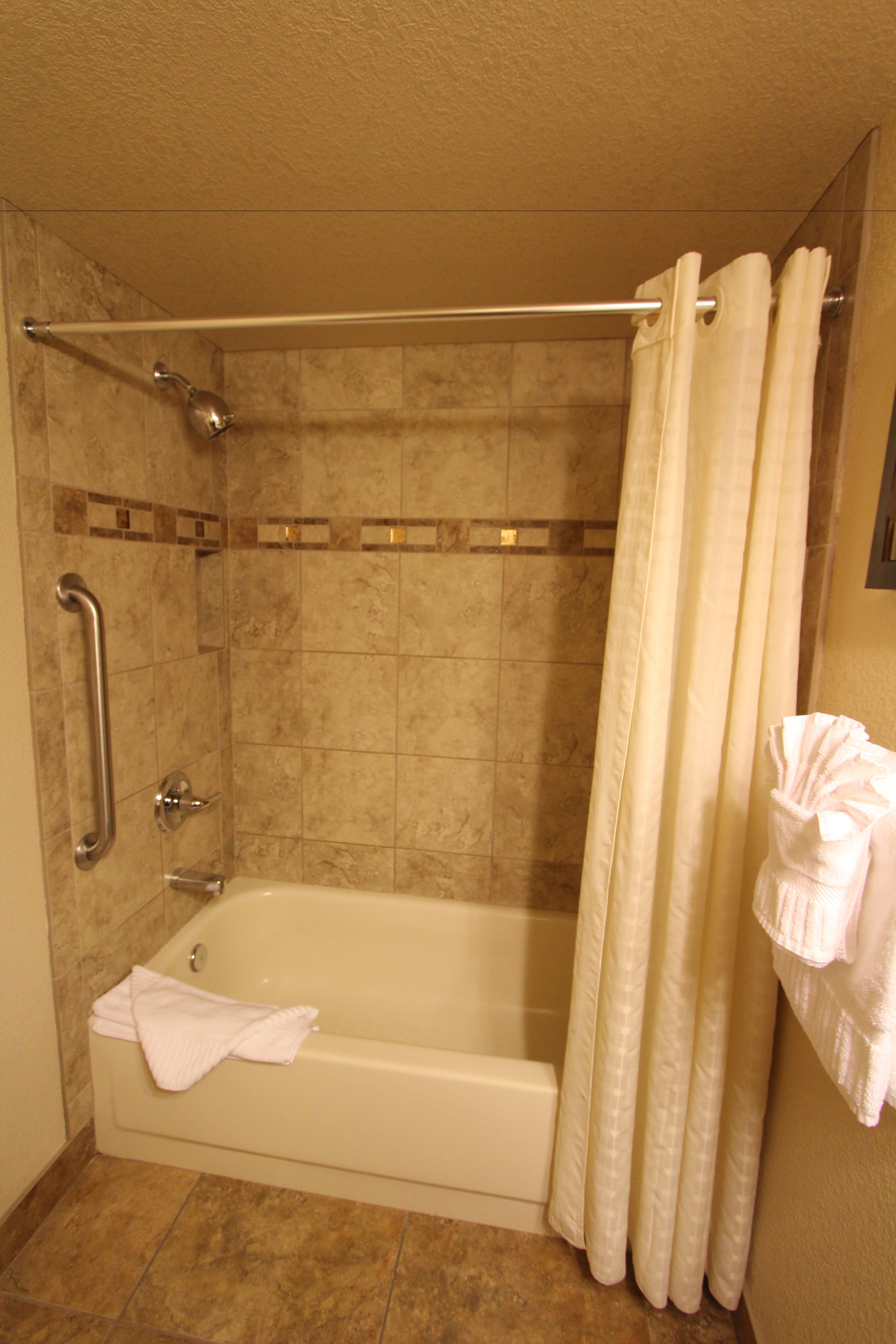 Une salle de bain équipée d’une baignoire, d’une douche et d’une barre d’appui.