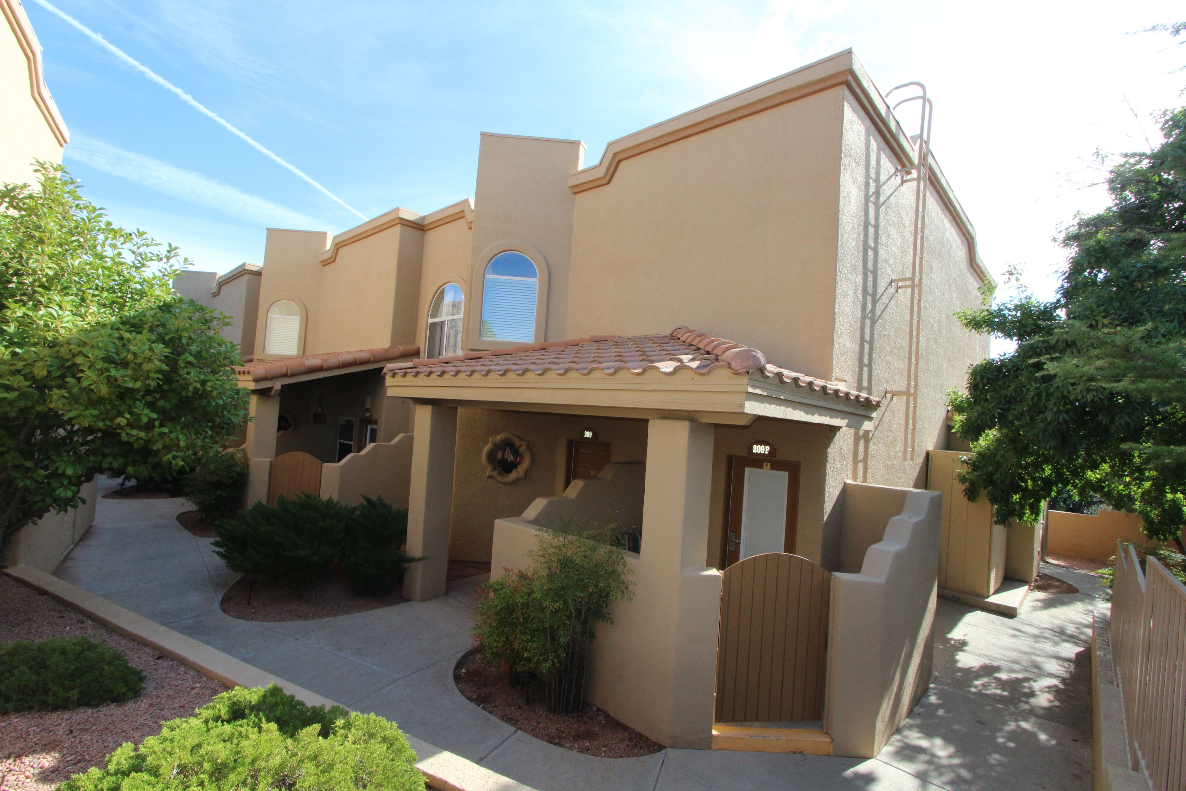 A building with a beige facade, a tiled roof, and a gated entrance.