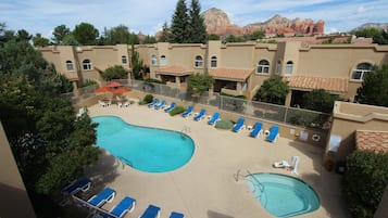 A hotel with a pool area, including lounge chairs and a smaller pool.