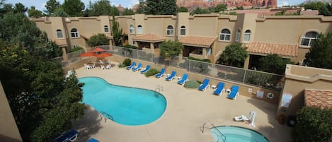 A hotel with a pool area, including lounge chairs and a smaller pool.