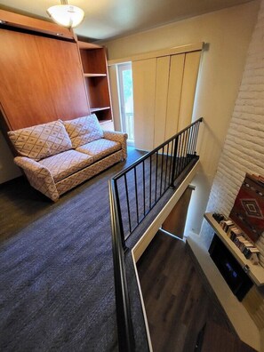 Un espace de vie de style loft comprenant un canapé, un escalier et une cheminée.