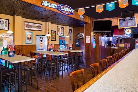 A restaurant with multiple tables and booths, a neon sign reading "Bud Light", and various sports memorabilia on the walls.