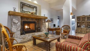 A cozy living room with a stone fireplace, wooden furniture, and a striped sofa.
