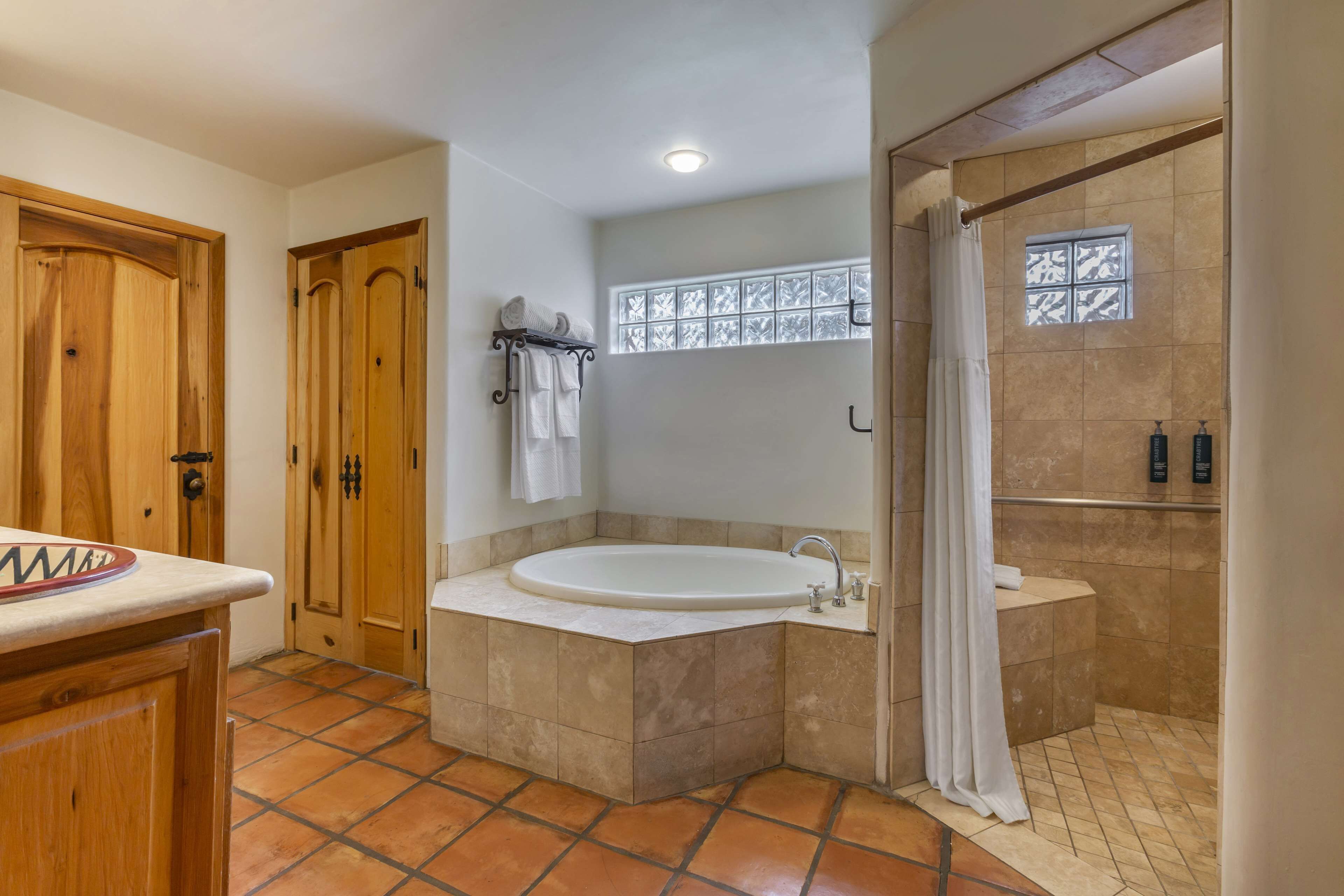 A bathroom with a bathtub, shower, and a window with a decorative screen.