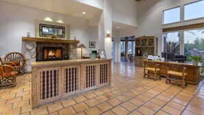 A spacious lobby with a stone fireplace, wooden chairs, and a large window offering a view of the outdoors.