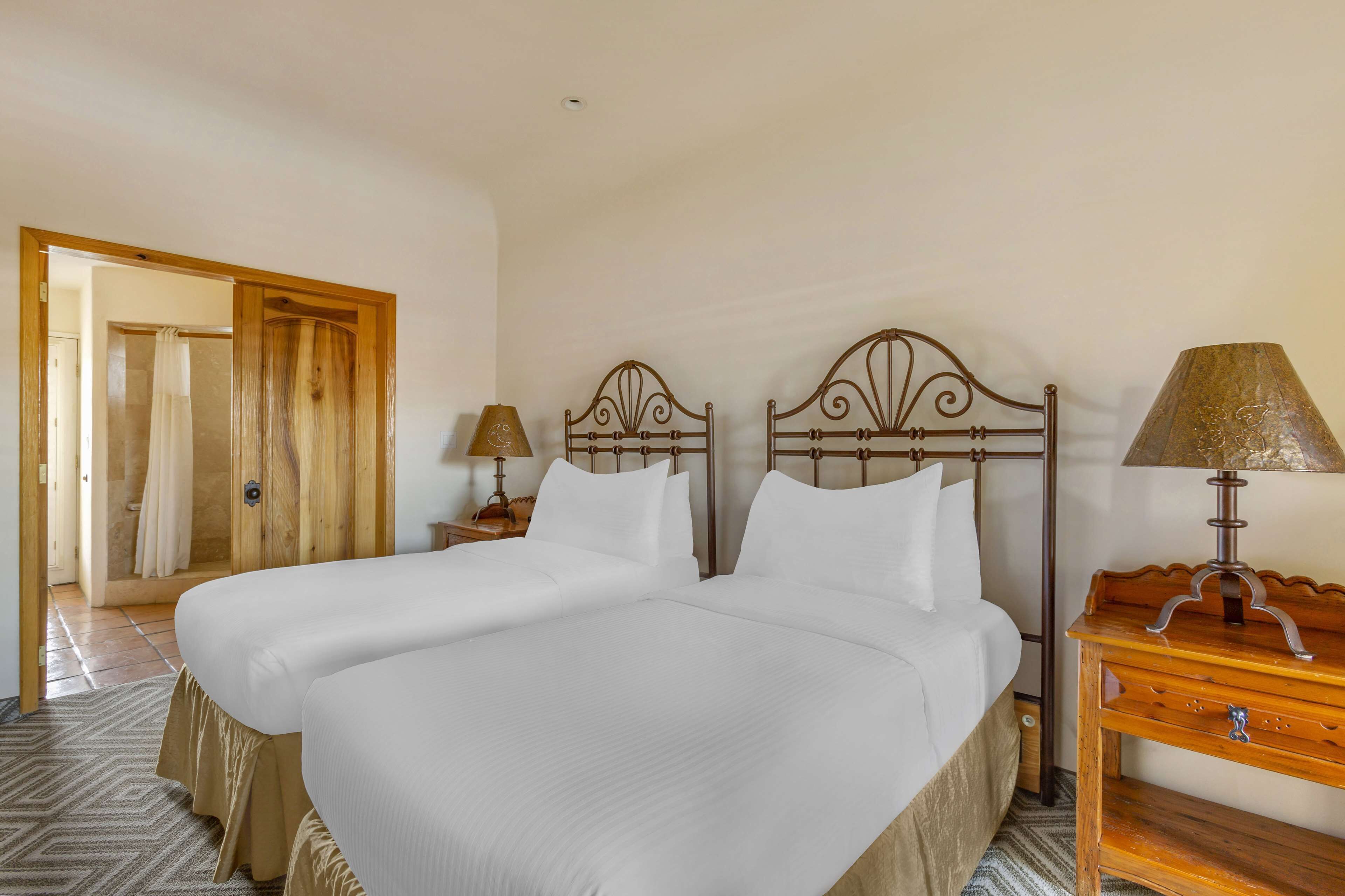 Un lit double avec une tête de lit en bois, une table de chevet avec une lampe et une commode en bois.