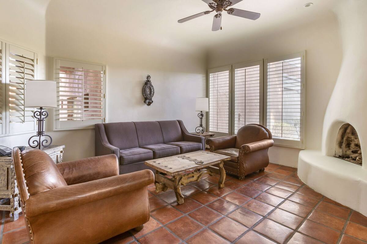 A living room with a brown leather sofa, a wooden coffee table, and a fireplace.
