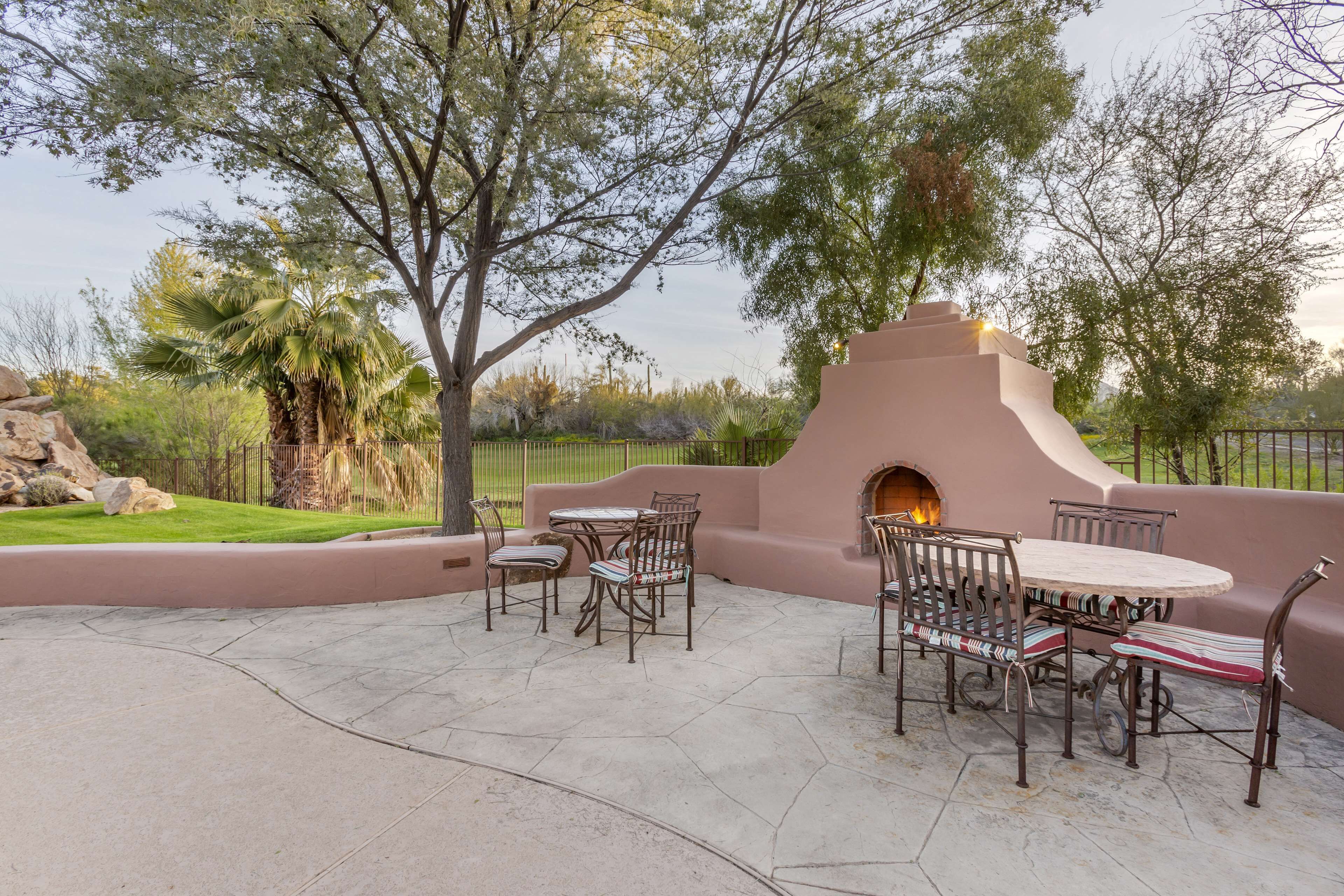 An outdoor patio with a stone floor, a round table, and chairs.