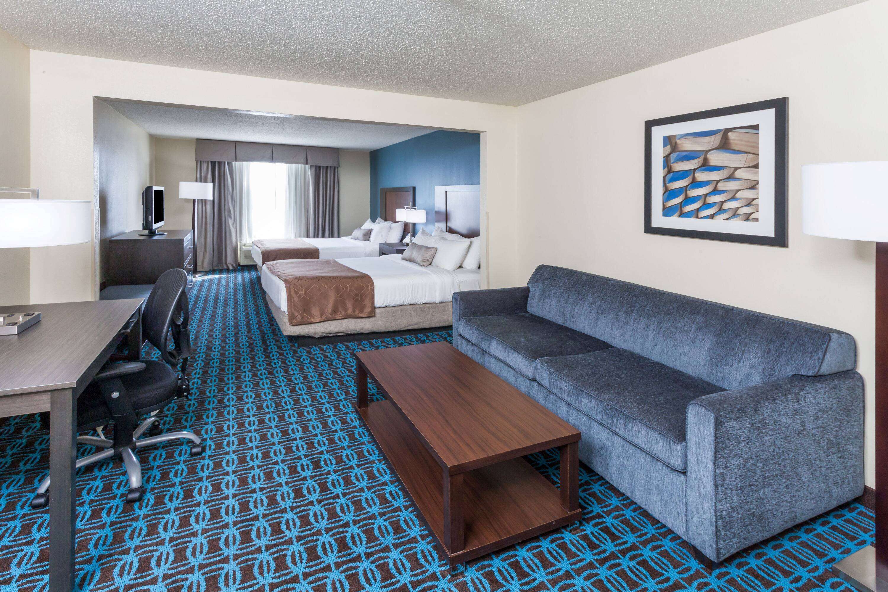 A hotel room with a bed, a sofa, a desk, and a TV.
