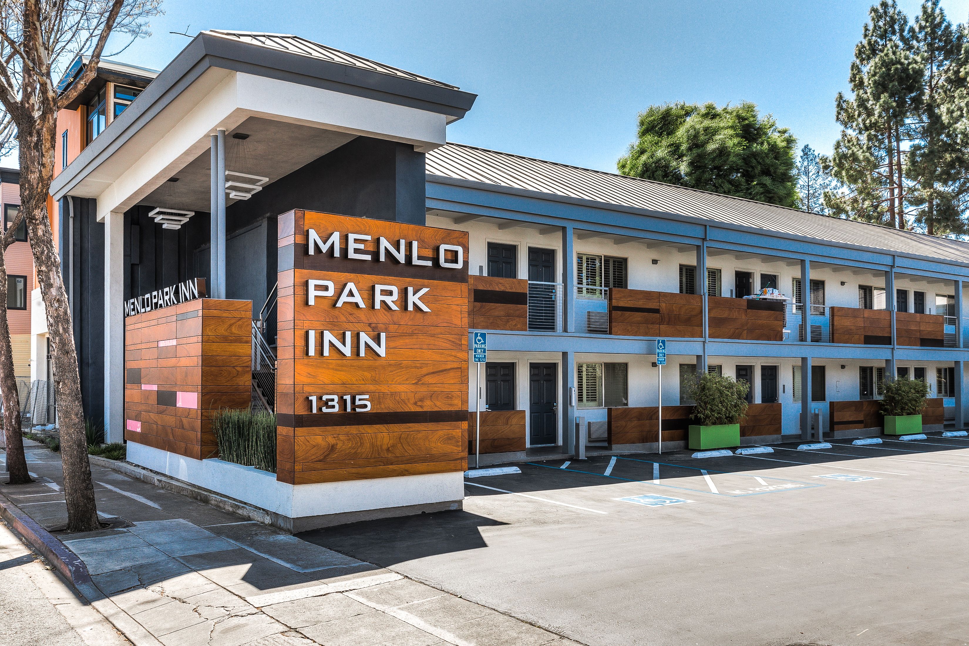 Edificio moderno del Menlo Park Inn con un cartel llamativo, estacionamiento y entrada cubierta.
