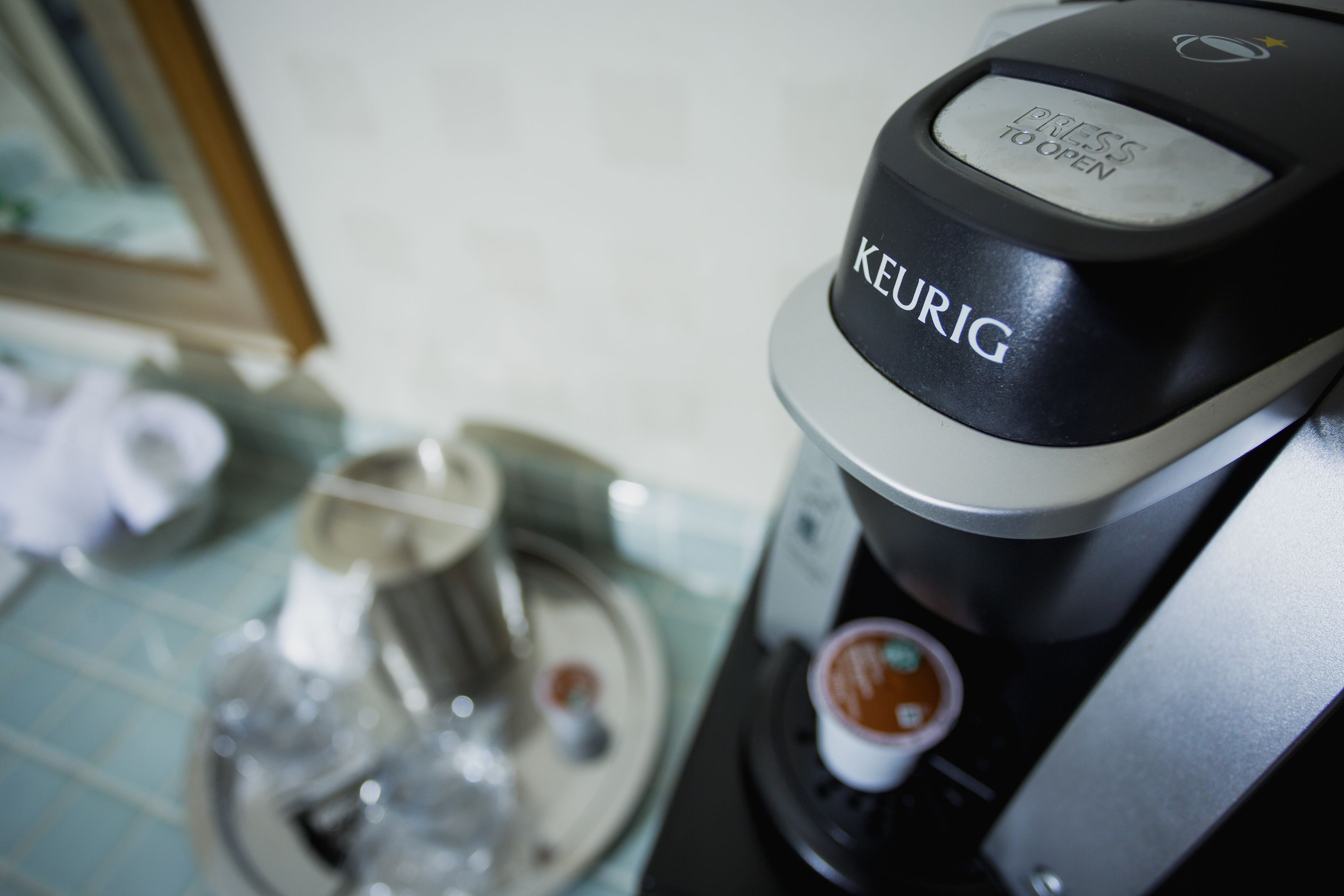 A Keurig coffee maker with a "Press to Open" button and a coffee pod holder.