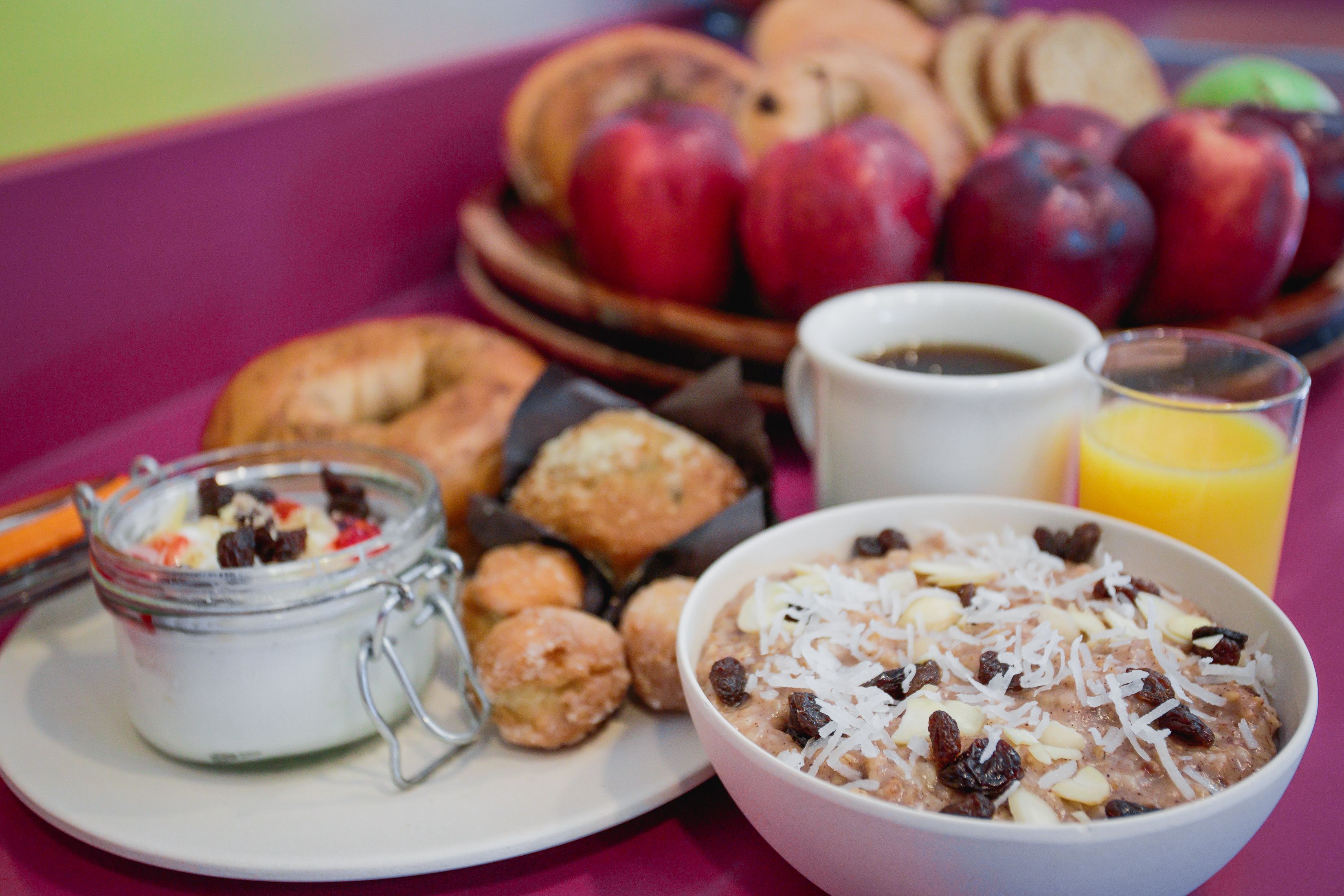 A breakfast setting with a plate of pastries, a bowl of oatmeal, a glass of orange juice, and a cup of coffee.