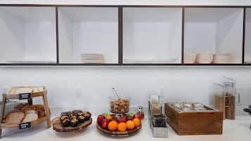 Een buffetgedeelte met diverse etenswaren, zoals brood, fruit en toevoegingen.