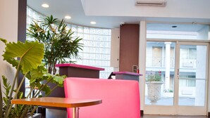 A bright room with a pink chair, a wooden table, and a large potted plant. - Menlo Park Inn (Menlo Park)