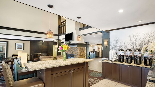 A hotel lobby with a large seating area, a kitchen counter with coffee machines, and a stone fireplace. - Sonesta ES Suites San Diego - Rancho Bernardo (San Diego)