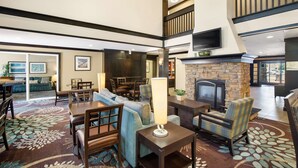 A spacious lobby with a fireplace, seating area, and a television mounted on the wall. - Sonesta ES Suites San Diego - Rancho Bernardo (San Diego)